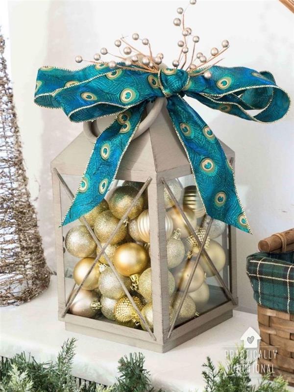 sivý lampáš vyplnený zlatými a striebornými vianočnými guľami, ozdobná modrá stužka, luxusná elegantná vianočná dekorácia