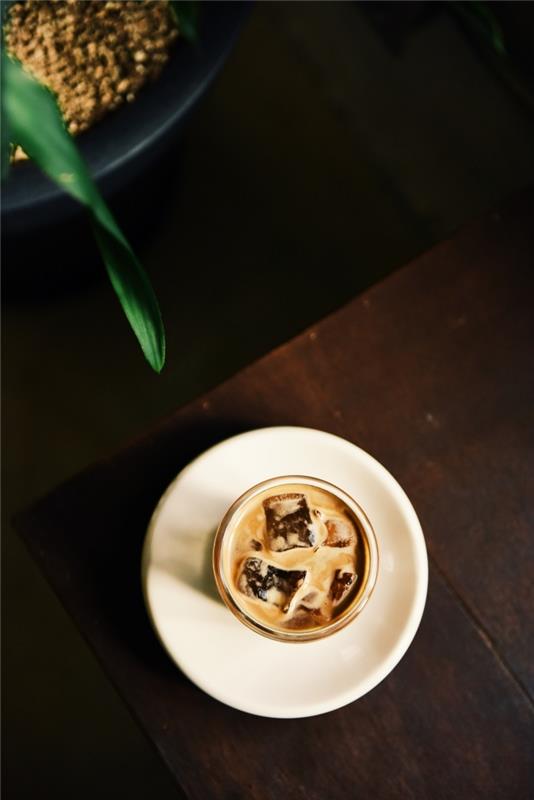 ako si vyrobiť jednoduchú domácu ľadovú kávu, pohár naplnený chladeným latte s kockami ľadu na okrúhlom tanieri