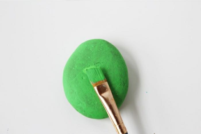 Idee lavoro artigianale con un sasso dipinto di colore verde con un pennello