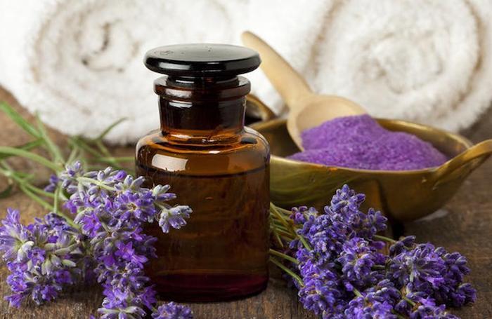 fördelarna med lavendel och hur man införlivar den i vårt dagliga liv två ihoprullade handdukar bakom lavendelprodukter