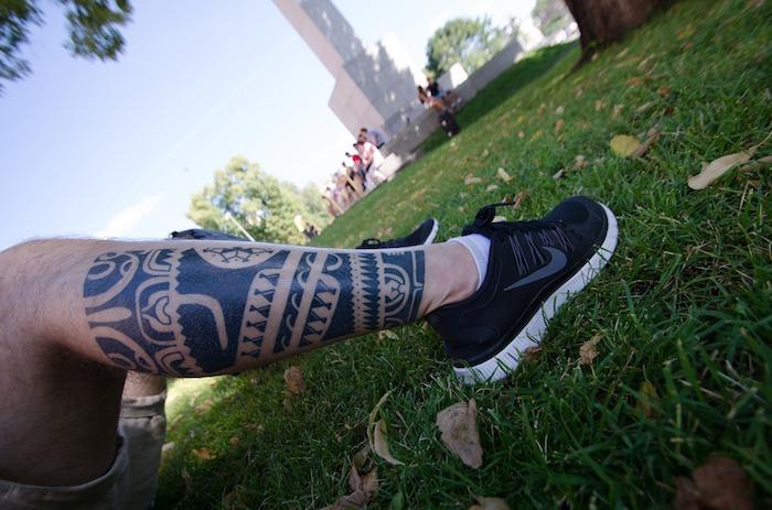 manstatuering, grönt gräs, eftermiddag i naturen, polynesisk tatuering, tatuering på ben, beige man shorts