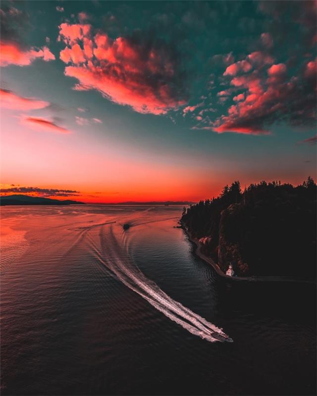 príklad bezplatnej tapety, pekná fotografia prírody s člnom na vode zafarbená západom slnka