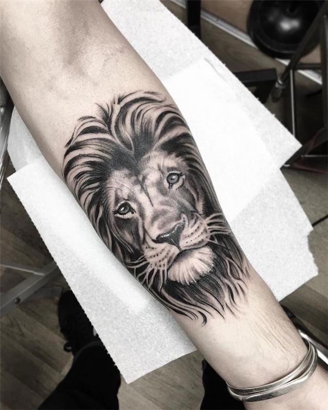 lejonhuvud, hand på vitt papper, silverarmband, tatuering under ärmhylsa