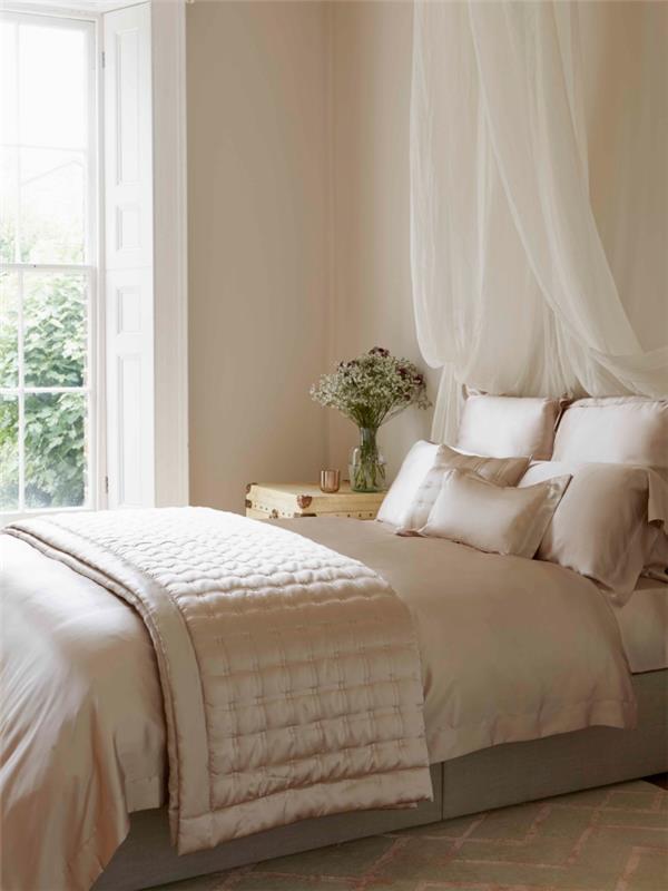 färg för romantiskt sovrum med beige väggar och vitt fönster med himmelssäng och sängbord i ljust trä