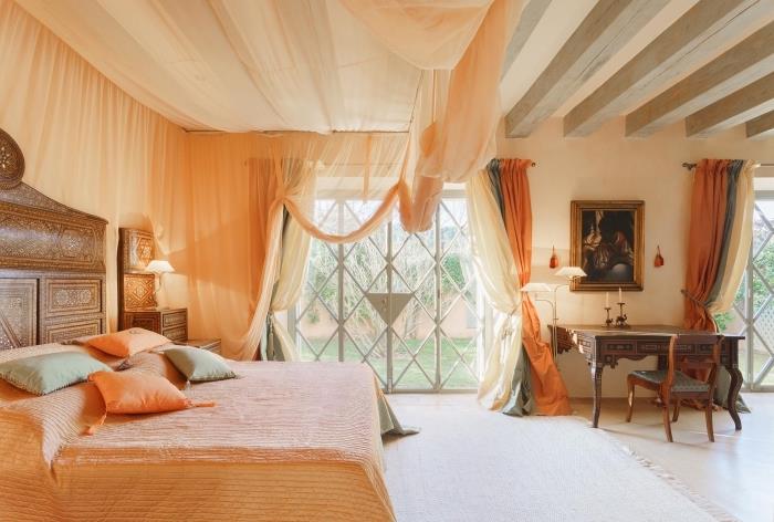 priestranná dispozícia spálne s béžovými stenami s dreveným trámovým stropom a svetlou drevenou podlahou, čelo v orientálnom dizajne