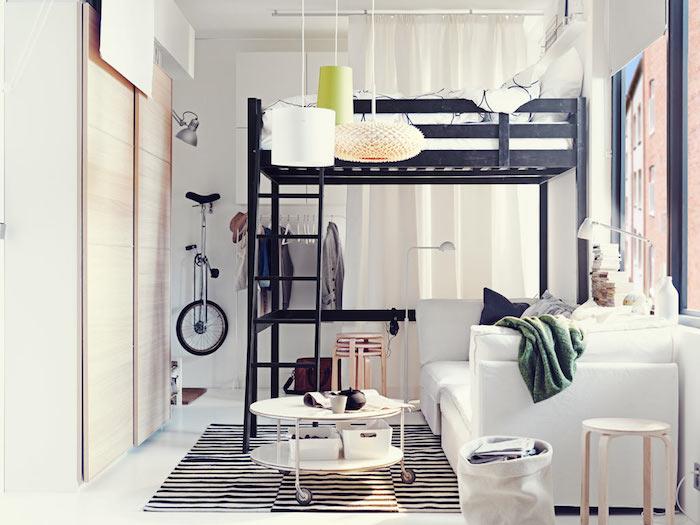 svart hög säng, vit soffa och runt soffbord med hjul på zebramatta, vita väggar, gardiner för att täcka ett fönster, garderob med skjutdörr i trä