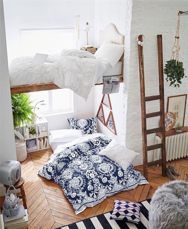 liten lägenhet med hög träsäng, parkettgolv med madrass på golvet och blåvita sängkläder, rustik trästege