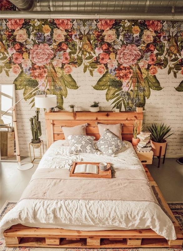 paletová posteľ s čelom z dreva vyrobeného na mieru, stena zdobená kvetinovým vzorom na bielych tehlách, kvetináče so zelenými rastlinami ako posteľ