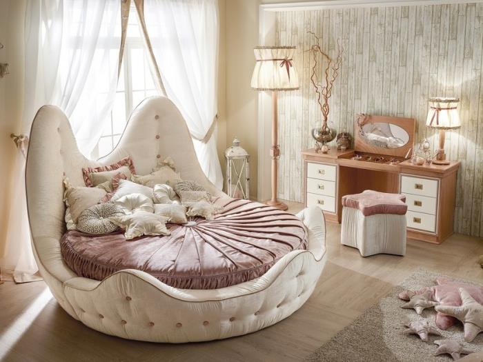 ecru -färg i det romantiska sovrummet med rund säng och vintage ljusa trämöbler, beige och pulverrosa dekoration
