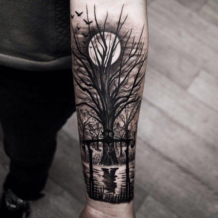 Tatuaggi sulla spalla uomo con il disegno di una foresta al tramonto con albero e lago