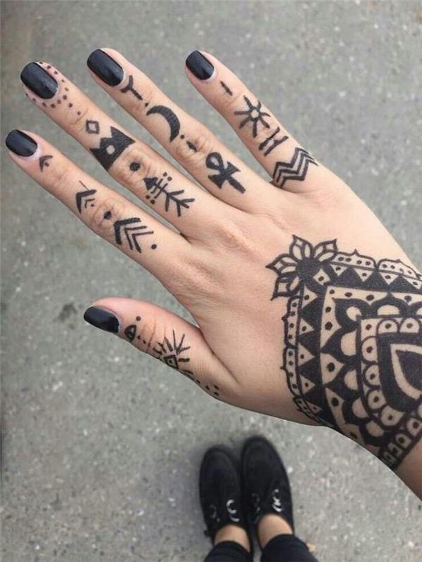 Tatuaggi sulle mani di una ragazza con tanti simboli e disegno mandala sul polso