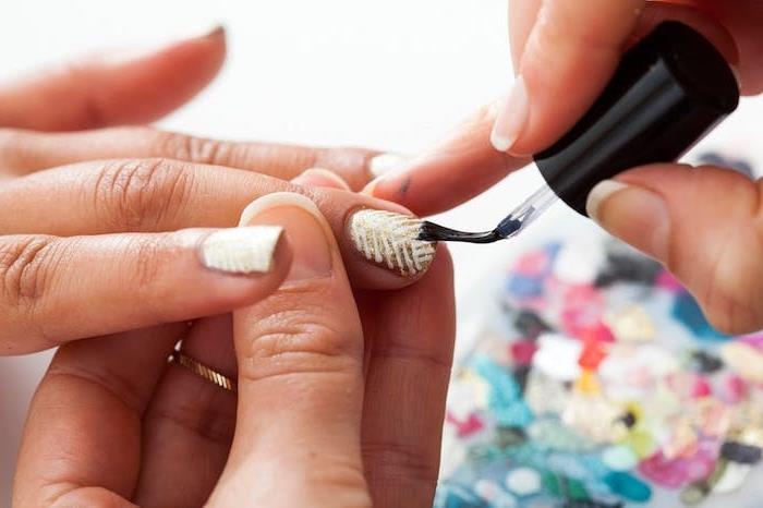 nápad, ako urobiť ľahký nail art na Vianoce, lak na nechty so zlatým a trblietavým efektom a biele čiary, krycí lak