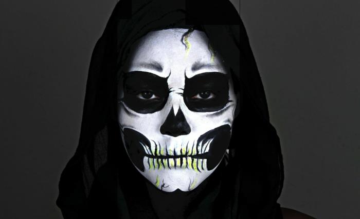 hlava halloweenskej kostry, čierne líca, prázdne čierne oči, bielo namaľovaná tvár