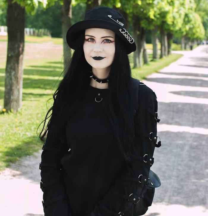 gotisk stil halloween häxmakeup, svart läppstift, blekt ansikte, rosa smink runt ögonen, halsband med halsband, bowlerhatt, gotisk blus