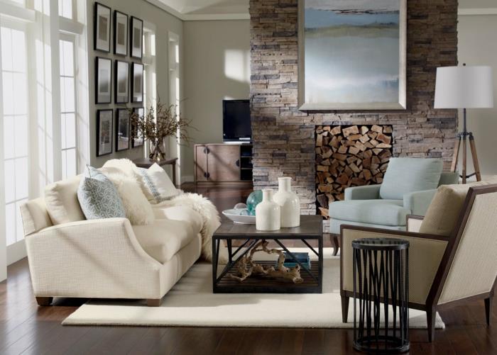 elegant och rustik lantlig inredning, brun parkett, vit soffa, soffbord i trä, öppen spis i sten, grå och blå fåtölj, vit matta
