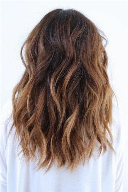 lockigt hår med blond balayage och medelfärgad hårfärg, bär av kvinna i vit tröja
