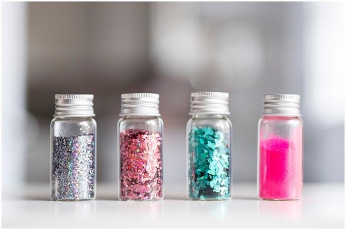 små glasbehållare fyllda med glitter och glitterpulver, idé för manuell aktivitet 2 år, återvinning av liten glasflaska