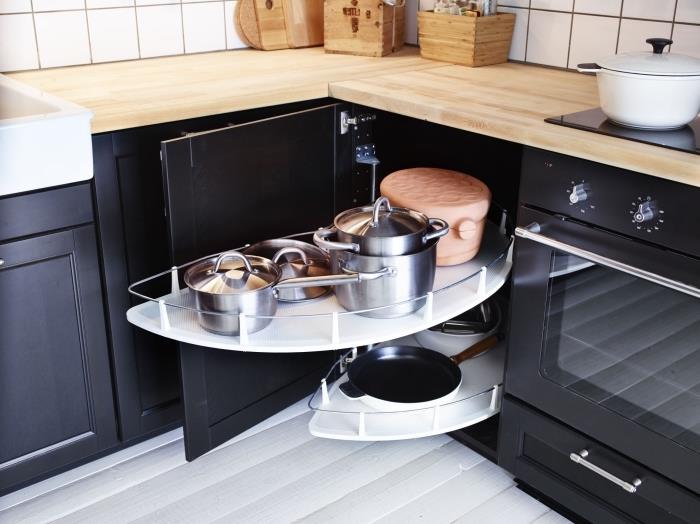 nízka kuchynská rohová skrinka s dvoma melamínovými doskami, ktoré sa vysúvajú pre ľahký prístup do kuchynského riadu, nízke drevené a čierne kuchynské skrinky, kontrastujúce s bielymi stenami a podlahou
