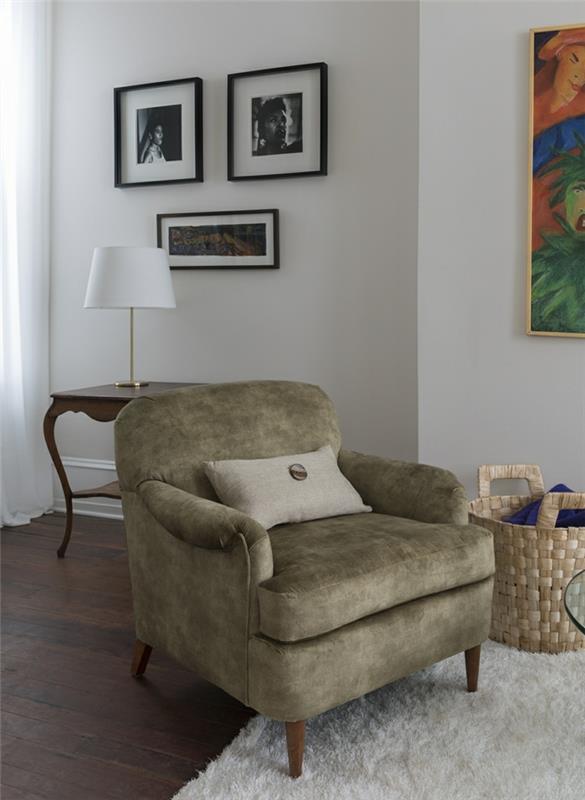 veľké olivovo zelené zamatové kreslo, malý obdĺžnikový vankúš s logom, klasická obývačka, tri malé obrázky s čiernymi rámami a veľký obrázok so zlatým rámom, prepracovaný nábytok