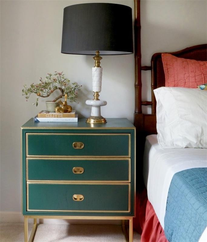nočný stolík s úložným priestorom premaľovaný na smaragdovo zelenú, bielu, modrú a červenú posteľnú bielizeň, čiernu nočnú lampu so zlatým podstavcom, béžový koberec