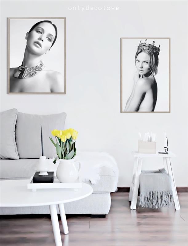 Škandinávsky nábytok v sivobielej obývačke, biela sedačka, sivé vankúše, hnedé parkety, biely konferenčný stolík, dekorácia čiernobielych fotografií