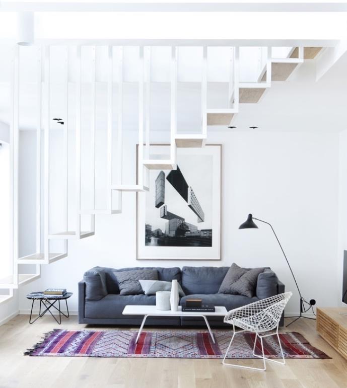 Škandinávsky nápad do obývačky so sivou sedačkou a orientálnym kobercom, bielym konferenčným stolíkom, kovovou stoličkou, bielym schodiskom