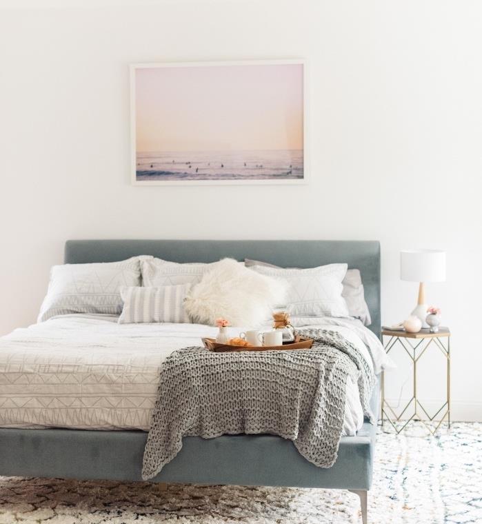 Škandinávsky nábytok, veľká modrá sivá posteľ, biela posteľná bielizeň, sivá prikrývka, prímorská krajinná foto deco, biely koberec s geometrickými vzormi