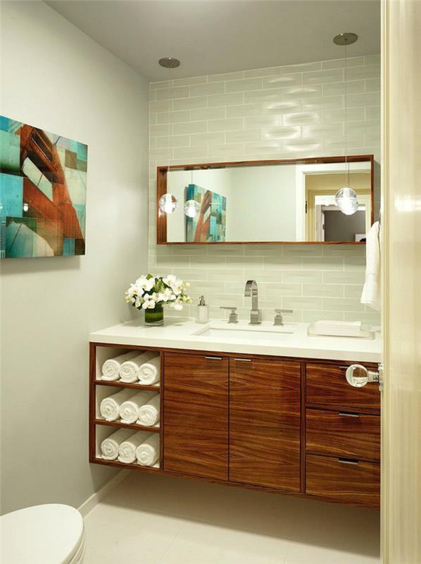 moderné usporiadanie toaliet, drevená skrinka, obdĺžnikové zrkadlo, dlaždice metra, abstraktný obraz, srolované uteráky