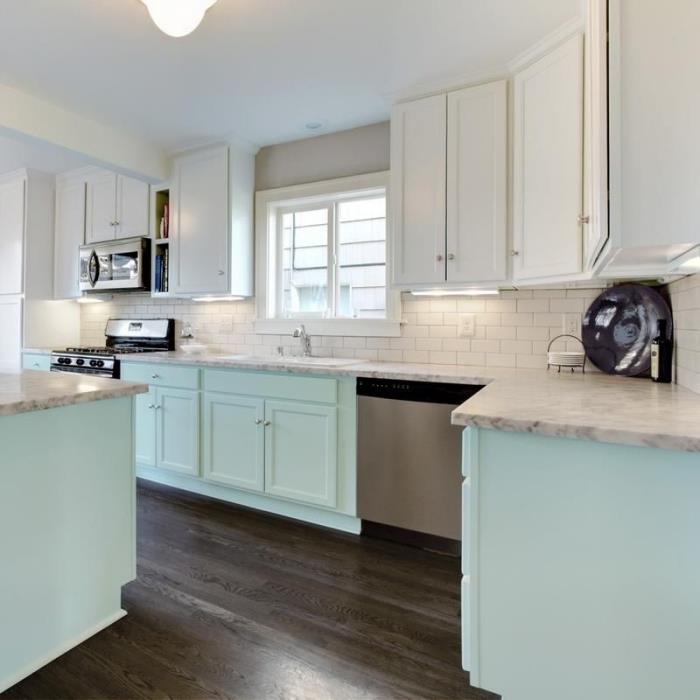 نماذج من خزائن المطبخ ذات اللون الأخضر البحري مع أسطح رخامية في مطبخ أبيض مع أرضيات خشبية داكنة