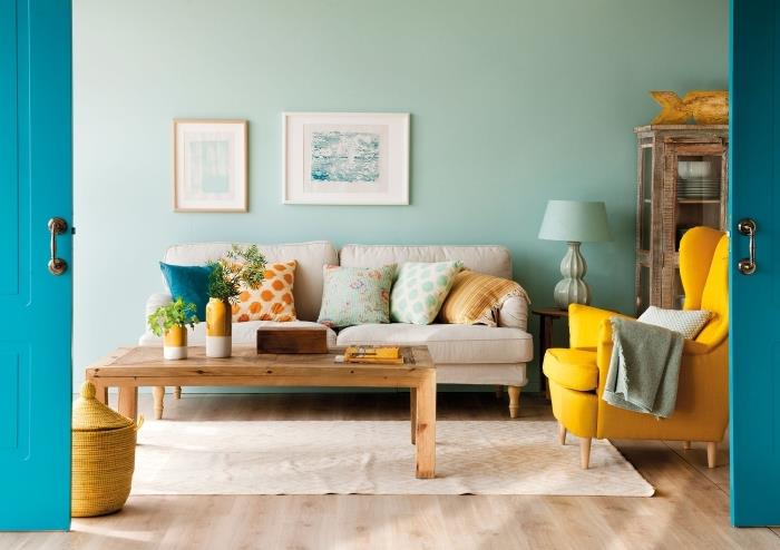nápad s horčicovo žltým dekorom s doplnkami alebo moderným nábytkom, obývačka s pastelovo zelenými stenami s parketami zo svetlého dreva a farebnými akcentmi