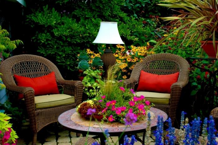 nápad na záhradný dizajn s obmedzeným priestorom, tkaný záhradný nábytok v hnedej farbe zdobený vankúšmi v zelenej a červenej farbe