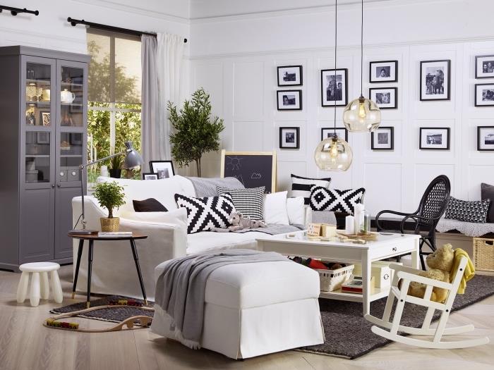 grå och vit vardagsrumsinredning som blandar industriella, skandinaviska och vintage stilar, med en stor mysig vit soffa, naturliga trä accenter och en vägg av svartvita ramar