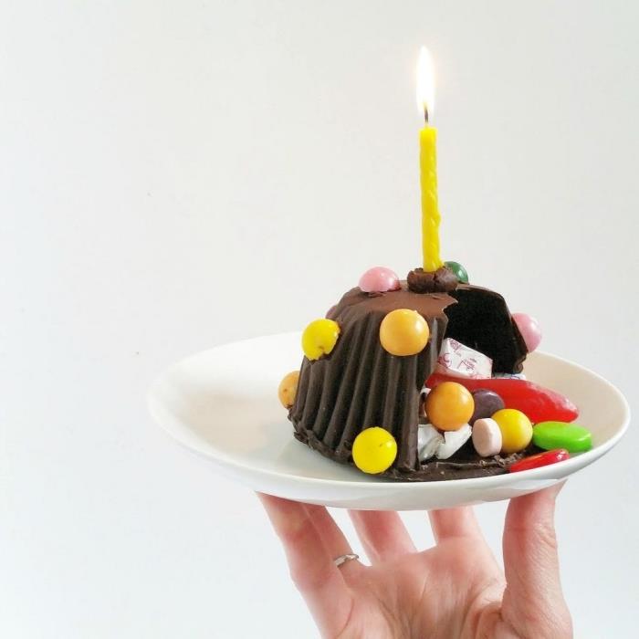 mini ihålig choklad pinata tårta som innehåller olika godis, med ett enda ljus