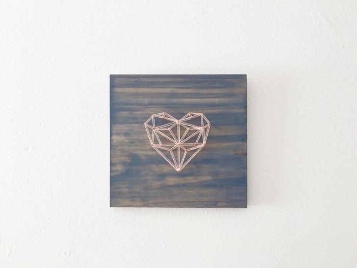 exempel på väggdekoration i minimalistisk stil med origamihjärta i vit och röd tråd på en träskiva