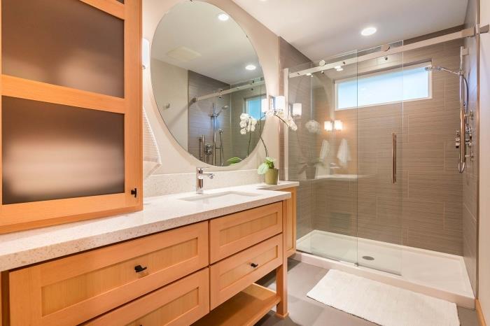 drevený a biely dizajn kúpeľne so sprchovým kútom, malá kúpeľňová dekorácia s veľkým okrúhlym zrkadlom a kvetmi