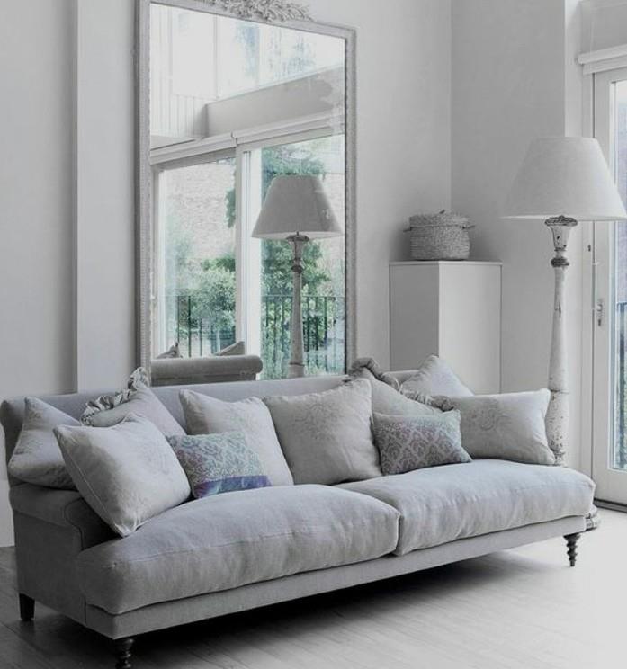 Soggiorno bianco e grigio, divano con cuscini colorati, grande specchio da parete