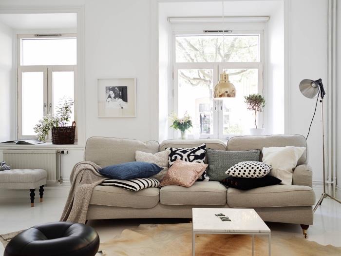 Škandinávsky nábytok v modernej severskej obývačke so sivou pohovkou, kobercom zo zvieracej kože, bielou maľbou na stenu, čiernym koženým sedadlom, farebnými vankúšmi, zlatým závesným svetlom