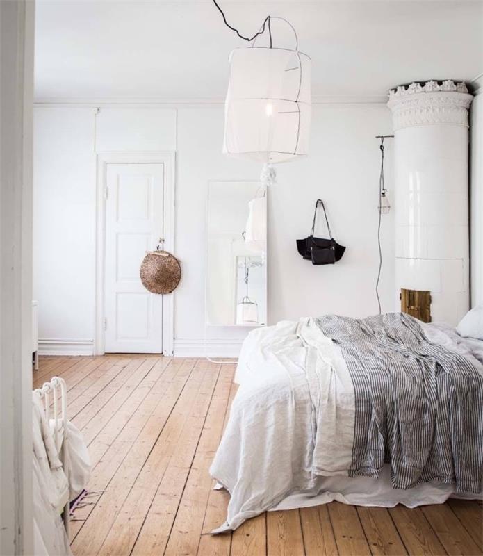 dekor so škandinávskym nábytkom v dizajnovej spálni, biela a čierna posteľná bielizeň, svetlé parkety, originálne biele závesné svetlo, biely krb