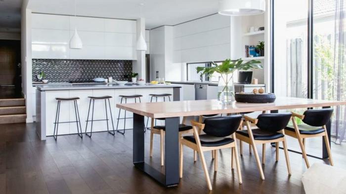 biela otvorená kuchyňa s bielym barom a čiernym splashbackom, jedáleň s dreveným a kovovým stolom a drevenými a čiernymi koženými stoličkami, hnedé parkety