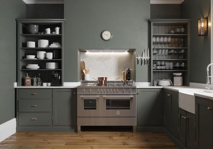 مثال على مطبخ مجهز باللون الأخضر مع العديد من الأرفف المفتوحة مع الأواني الفخارية البيضاء وأدوات المطبخ المكشوفة والموقد الأبيض العتيق والباركيه الخشبي البني