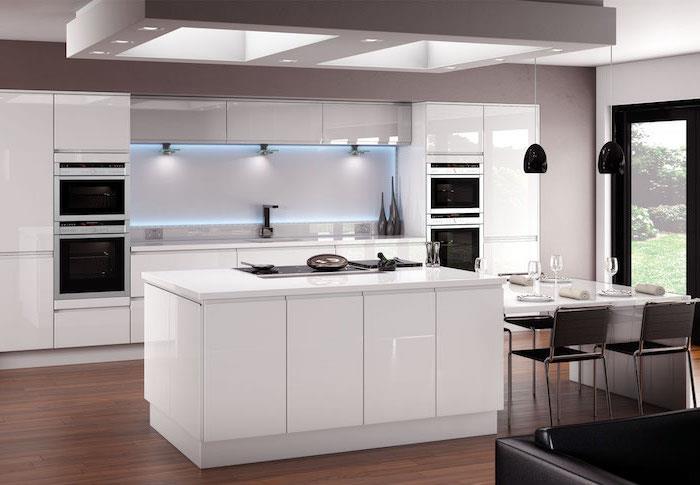 lågt köksskåp utan handtag i vitt med neonbelysning i blått, svart skinnsoffa och svarta hänglampor