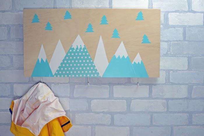 نموذج رف المعاطف الاسكندنافي من لوح خشبي مع الجبال المغطاة بالثلوج وأشجار التنوب ، جدار من الطوب الأبيض ، خطافات بسيطة