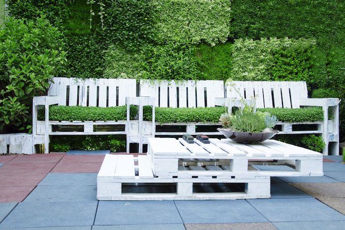 model záhradného nábytku z paliet s pohovkou z palety pokrytou trávou, skladaný konferenčný stolík z bielej palety, vonkajšia zelená stena