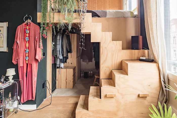 sovrum i svart och trä, säng på trä mezzanin plattform med madrass på golvet, inomhus gröna växter hippie chic inredning