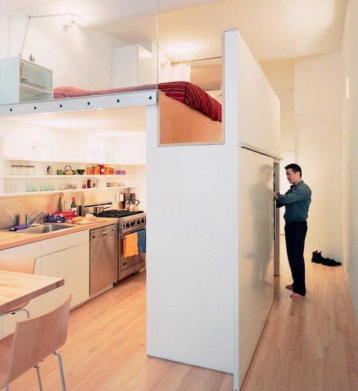 liten rymdlayout med säng ovanför ett kök som är öppet för matsal, platsbesparande tips i minimalistisk modern studioinredning