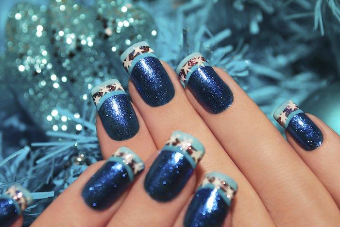príklad modelu nail art s modrým trblietavým lakom na nechty, svetlomodrou špičkou, čiernou čiarou a bielymi hviezdičkami