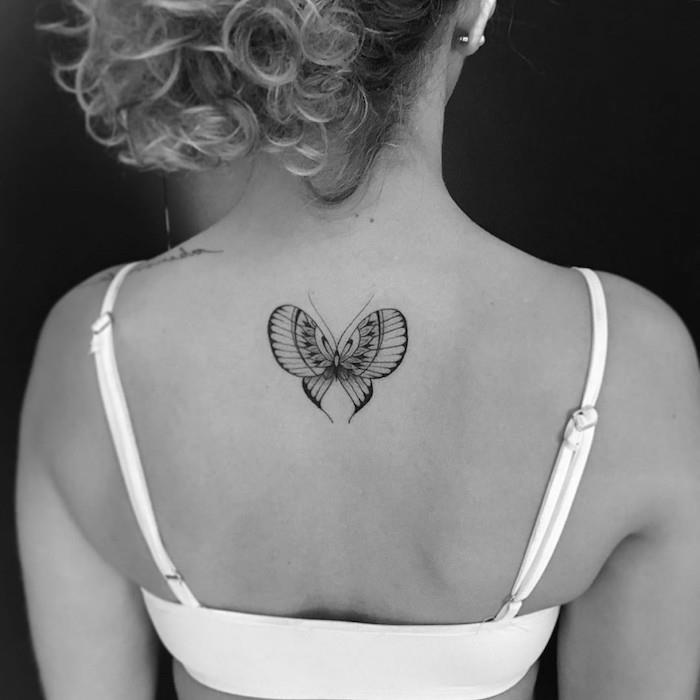 tetovací dizajn, biela a čierna fotografia, účes so zopnutými vlasmi, piercing do ucha, tetovanie motýľa na chrbte