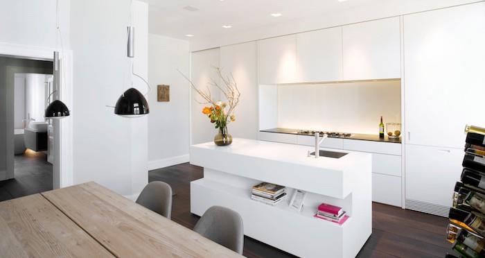 modernt vitt kök med mörkbrun parkett, köksfront och vit centralö, stänkbelysning, rått träbord