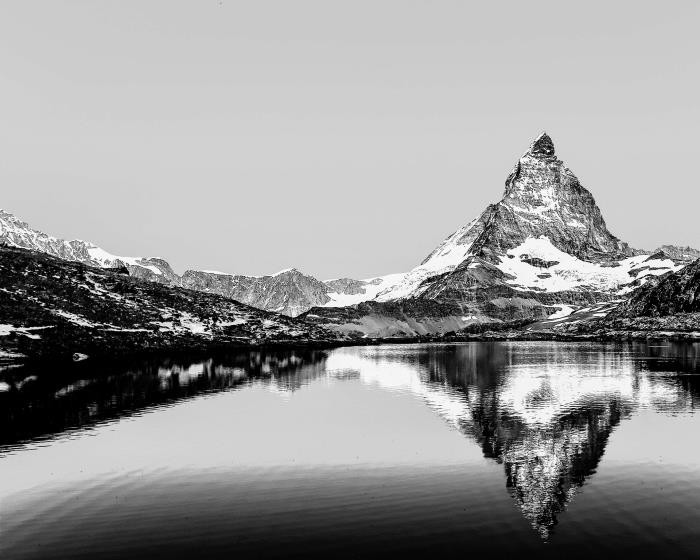 vacker svartvit bild av en hög topp som återspeglas i det isiga vattnet i sjön, de vackraste svartvita landskapsfotografierna