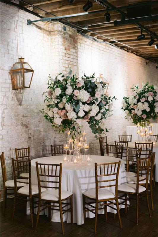 nápad na priemyselnú svadobnú výzdobu v svadobnej miestnosti s murovanými stenami, kvetinové dekoračné gule z kvetov, sviečky v pohároch na víno